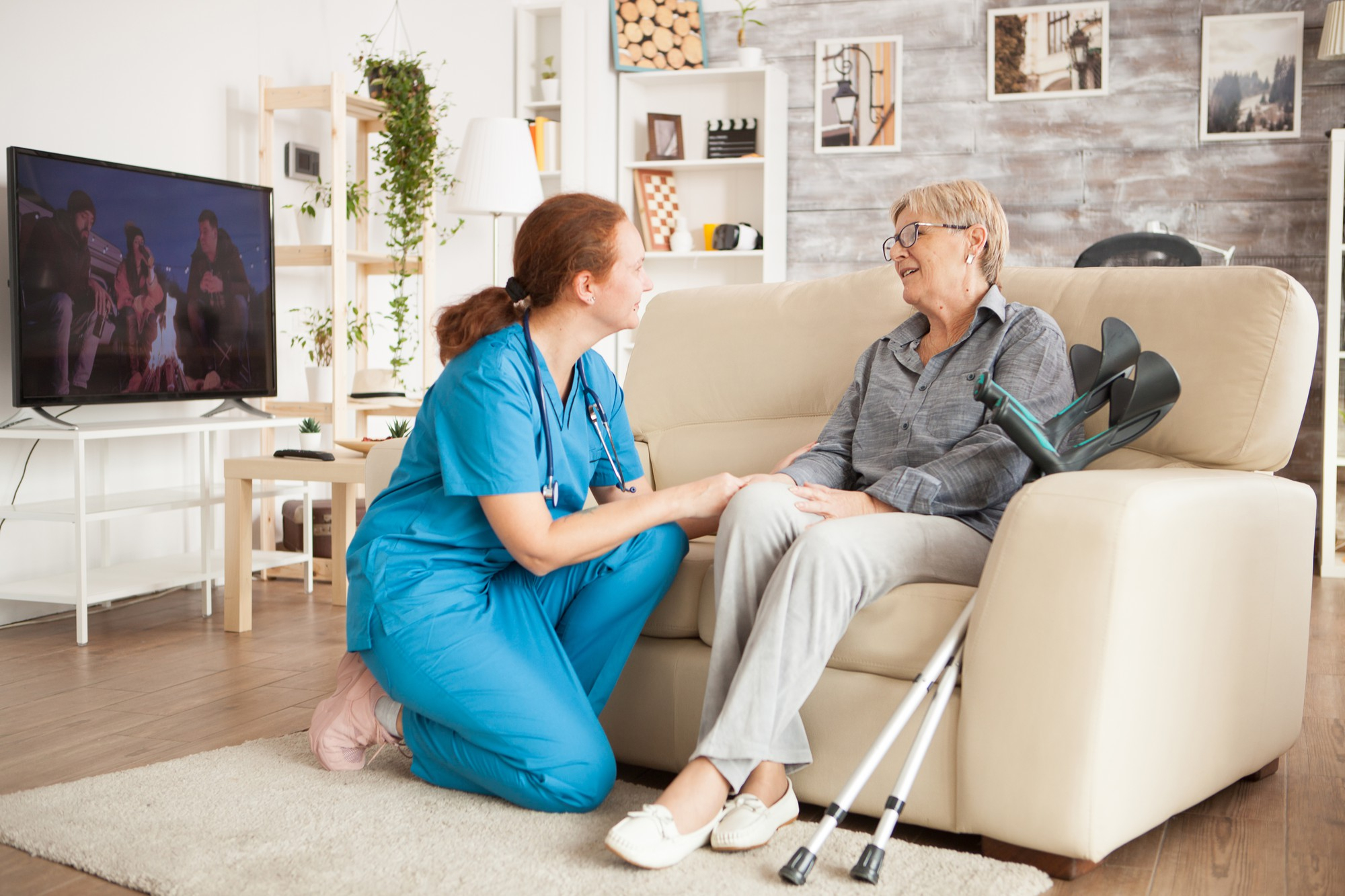Pflegerin im Gespräch mit einer älteren Dame auf dem Sofa